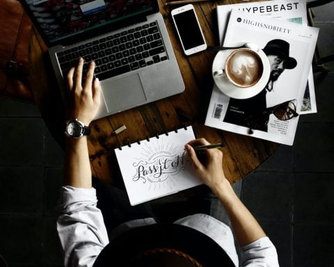 person sitting facing laptop computer with sketch pad