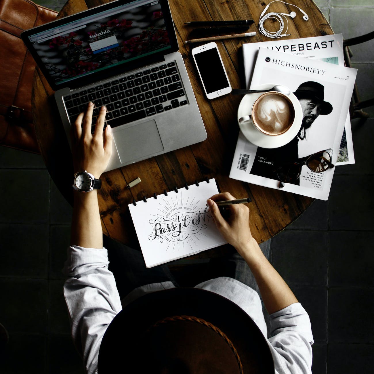 person sitting facing laptop computer with sketch pad